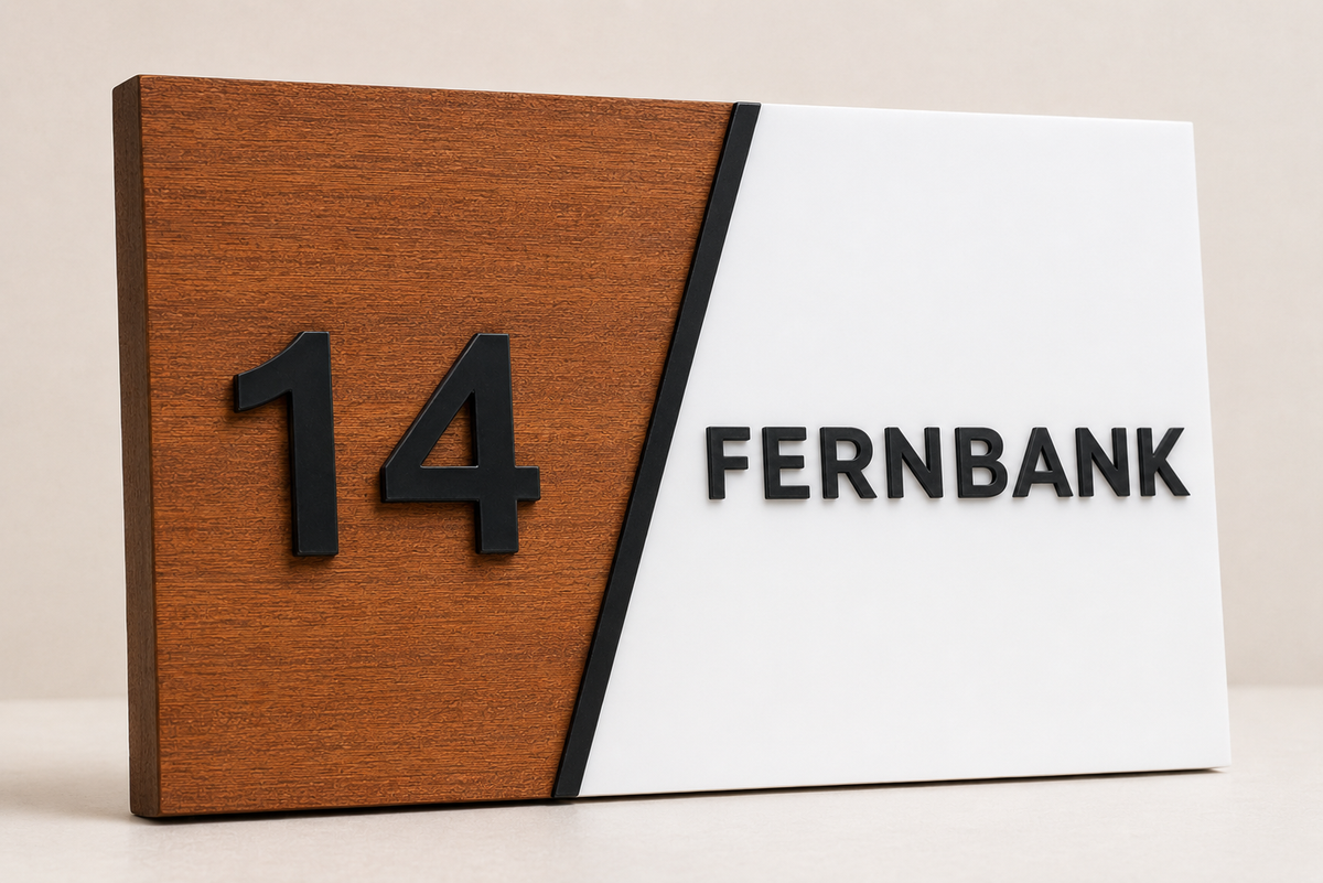A modern rectangular desk sign with a diagonal split design, featuring a warm wood-grain panel on the left with the raised black number 14, and a white panel on the right with the black text FERNBANK.lumorastudio.ie lumora craft studio