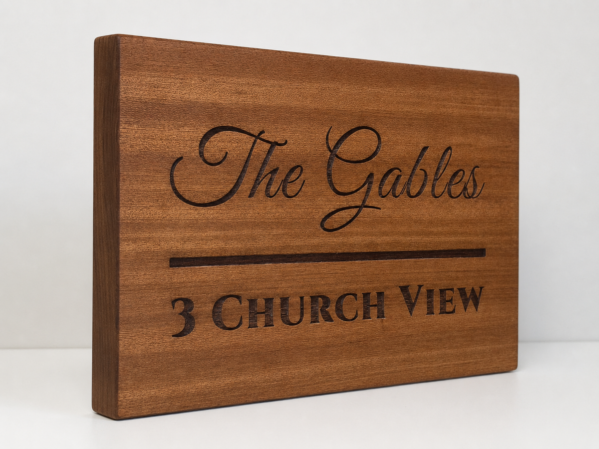 A rectangular wooden sign with a warm medium-brown wood grain finish, featuring the words 'The Gables' in elegant cursive and '3 CHURCH VIEW' in a dark serif font, set against a plain white background.lumorastudio.ie lumora craft studio