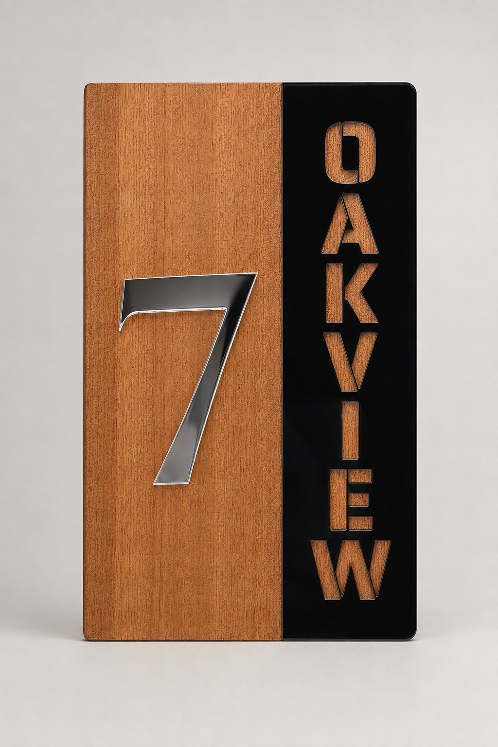A rectangular wooden plaque or sign with a vertical split design: the left half shows a warm medium-brown wood grain with a large metallic silver number 7, and the right half is black with the word "OAKVIEW" stacked vertically in a warm brown tone. The product is photographed against a clean light gray studio background.