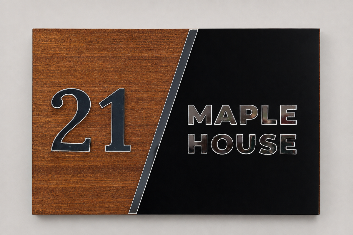 A rectangular house sign with a split design: the left half is warm brown wood grain with the number 21 in dark blue-gray, and the right half is black with the words MAPLE HOUSE in metallic silver letters. A thin metallic divider runs diagonally between the two halves.lumorastudio.ie lumora craft studio