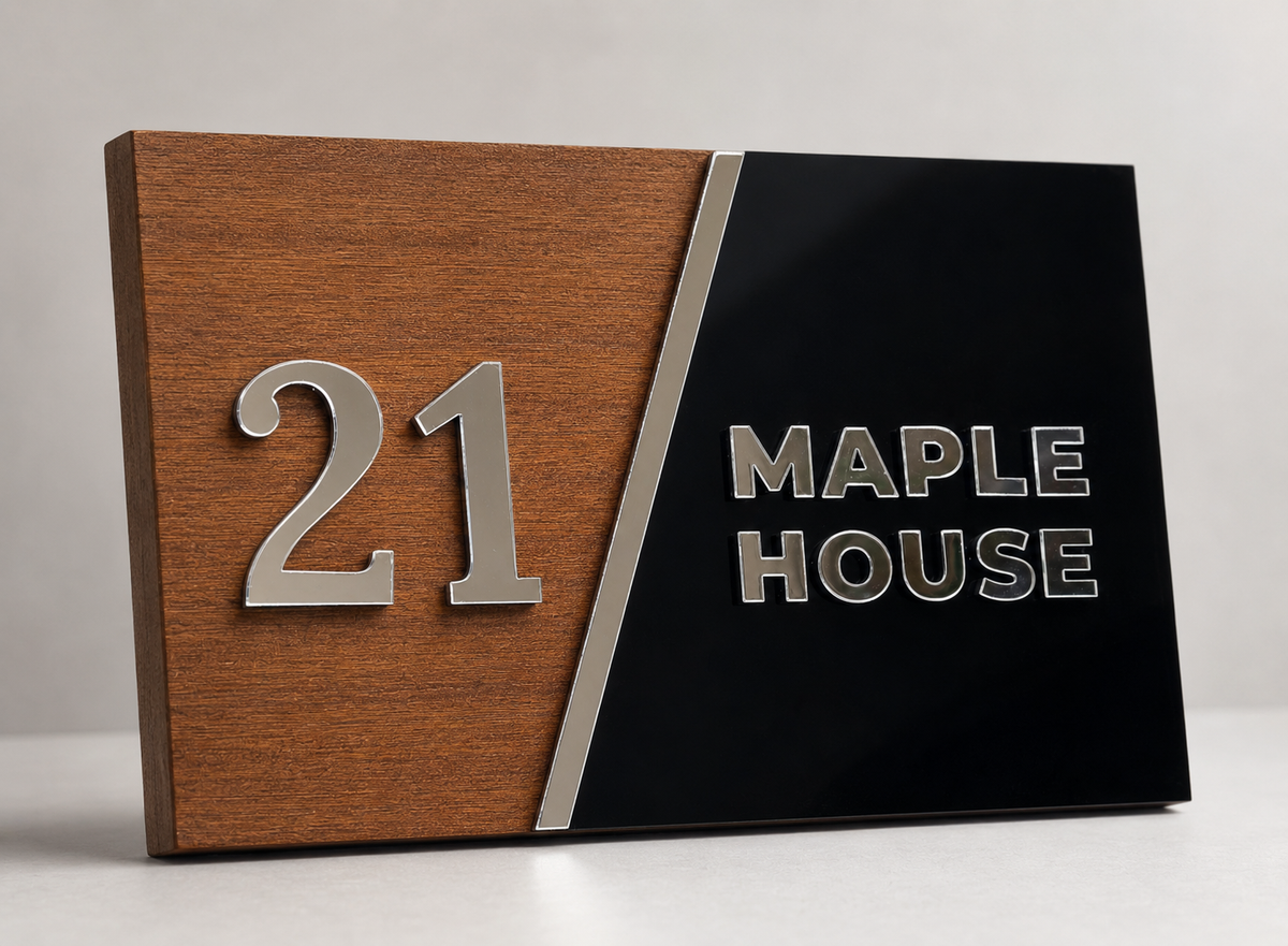 A modern house number plaque with a split design: a warm wood-grain panel on the left displaying the silver number 21, and a glossy black panel on the right with the silver text 'MAPLE HOUSE'.lumorastudio.ie lumora craft studio