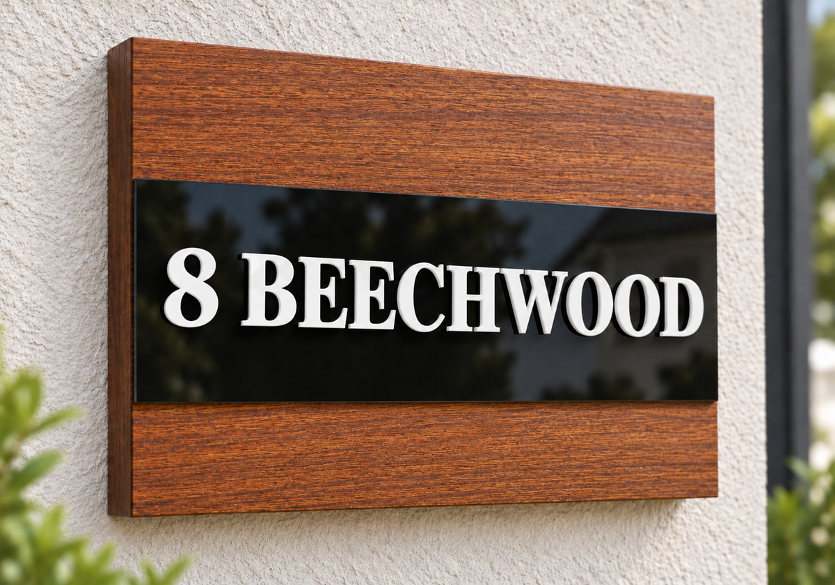 A custom wooden address sign mounted on a textured stucco wall. The sign features a black central panel with raised white lettering that reads '8 BEECHWOOD', framed by warm brown wood grain sections at the top and bottom.lumorastudio.ie lumora craft studio