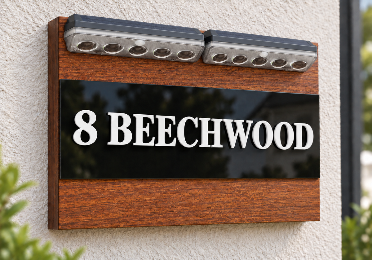 A custom wooden house number sign mounted on a textured beige stucco wall. The sign features a medium brown wood-grain frame, a glossy black center panel, and raised white lettering that reads '8 BEECHWOOD'.lumorastudio.ie lumora craft studio