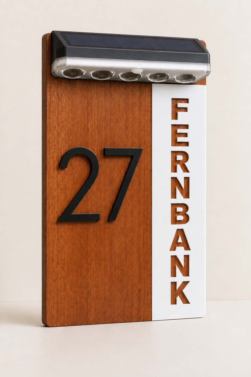 A vertical wooden house number sign with a warm brown wood-grain finish, a white vertical panel on the right reading FERNBANK in brown letters, and a black LED light bar mounted at the top, shown on a plain light beige background.