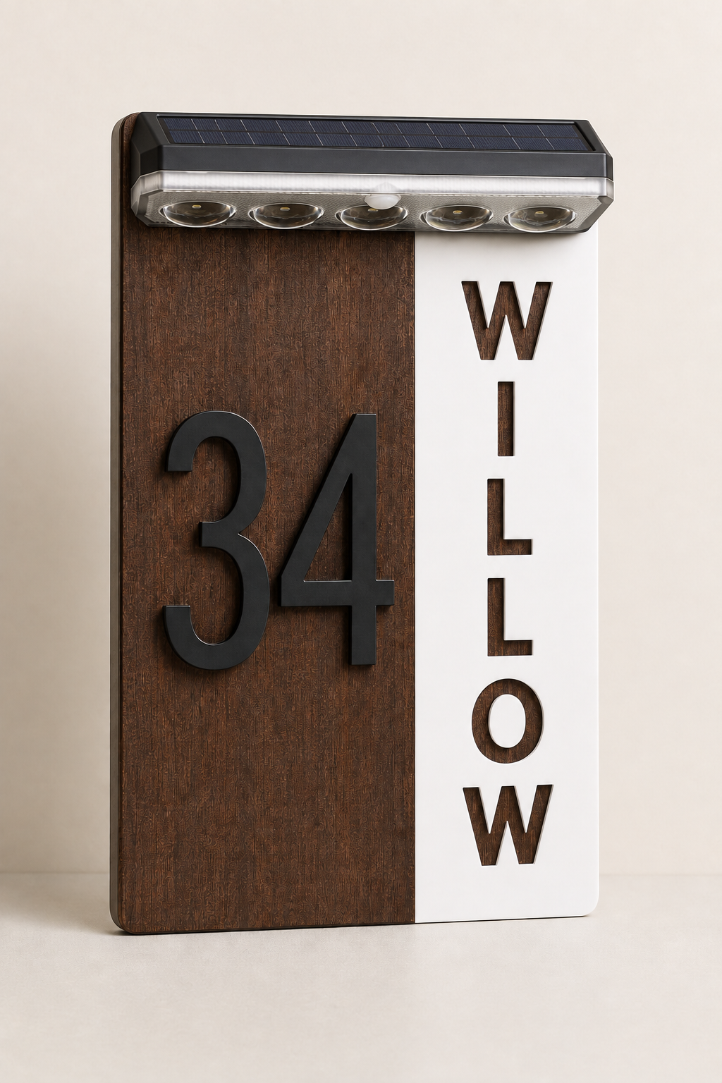 A vertical house number sign with a split design: dark brown wood on the left showing the number 34, and white on the right with the name WILLOW in large letters. A solar panel with four LED lights runs across the top.