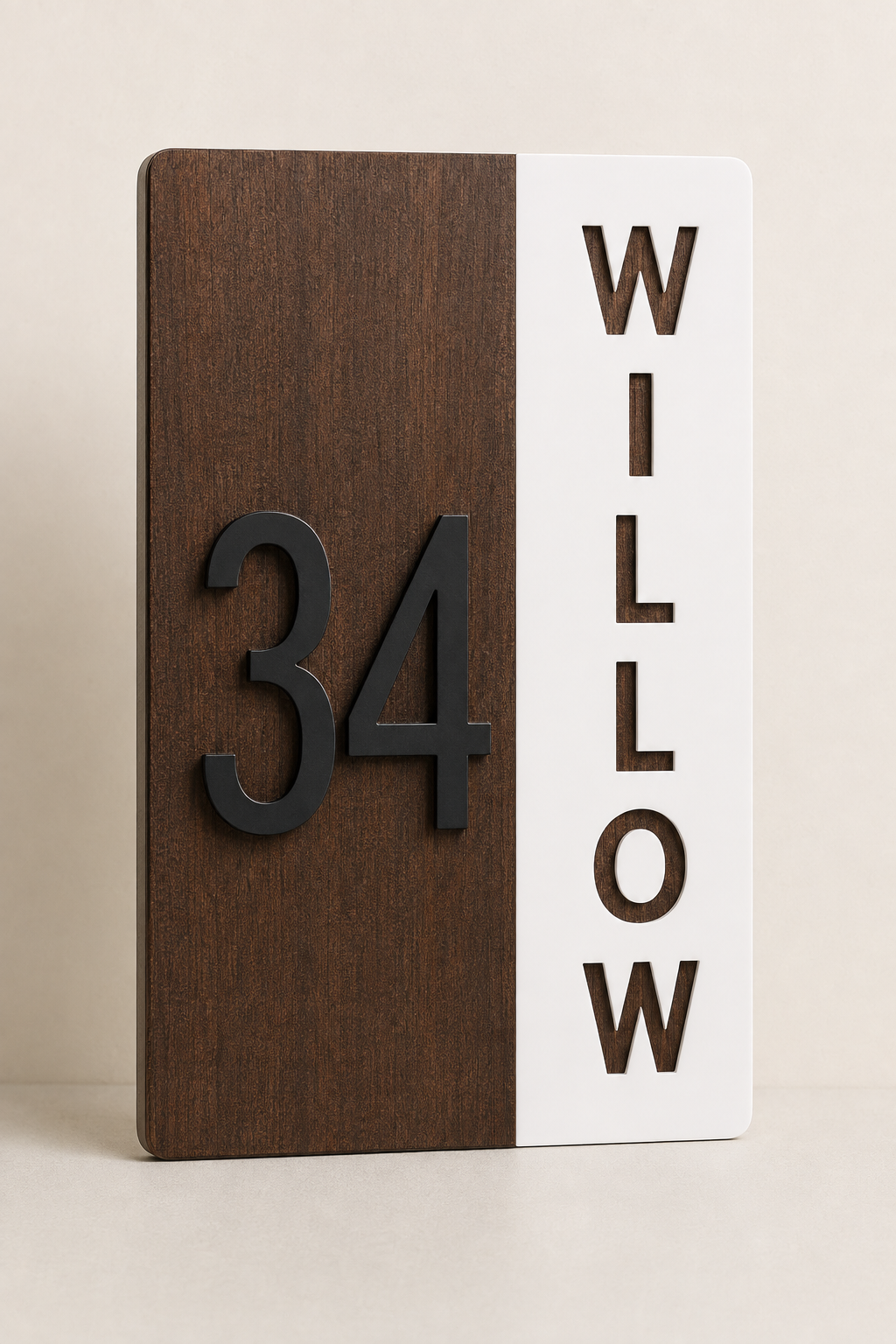 A modern two-tone wooden house number sign with a dark brown wood panel showing the number 34 and a white panel displaying the name WILLOW in vertical dark letters.
