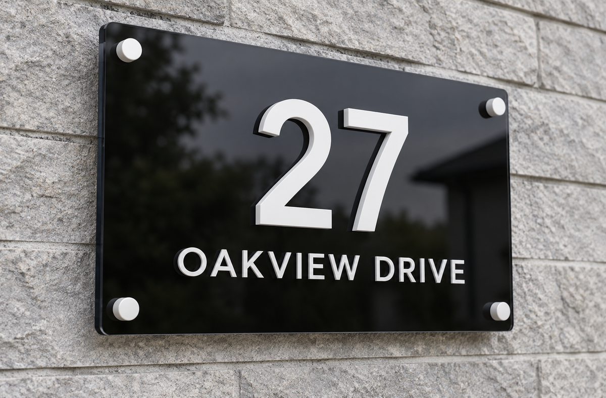 A modern black rectangular house number sign mounted on a gray stone wall, displaying '27 OAKVIEW DRIVE' in white lettering.lumorastudio.ie lumora craft studio