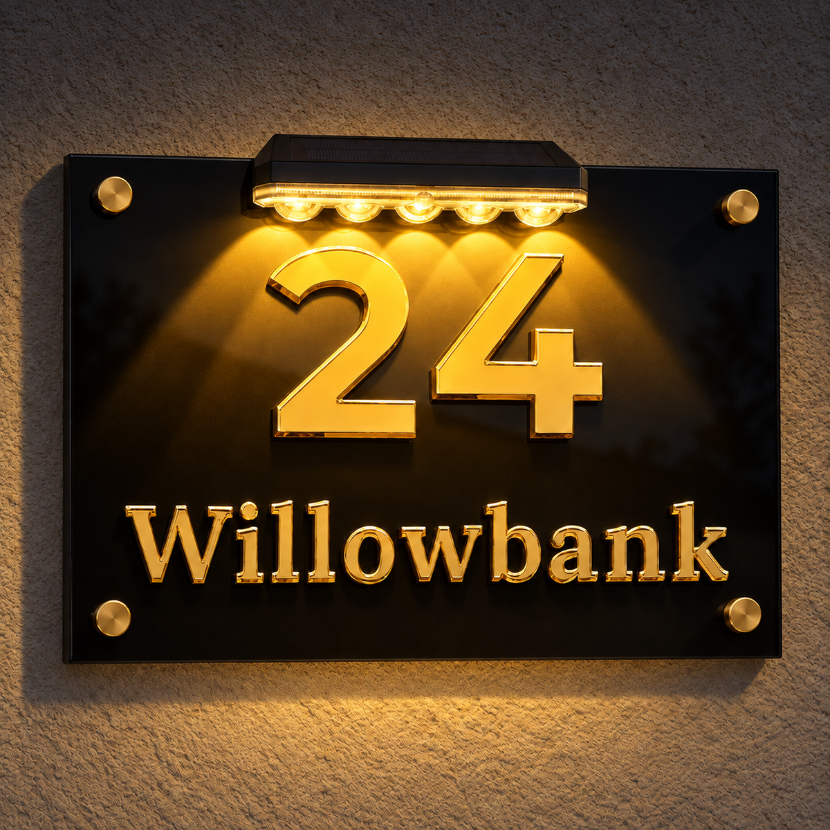 A black acrylic house number sign mounted on a textured wall, featuring illuminated gold numbers '24' and the name 'Willowbank' in gold lettering, with a built-in light bar above.lumorastudio.ie lumora craft studio