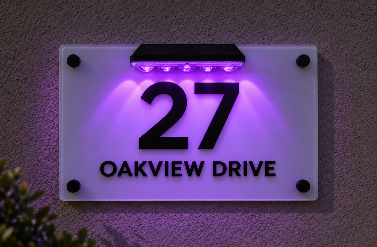 A modern acrylic house number sign mounted on a textured wall at night, illuminated by purple LED lights. The sign features the black numbers '27' and the black text 'OAKVIEW DRIVE' with black screw accents at the corners.lumorastudio.ie lumora craft studio