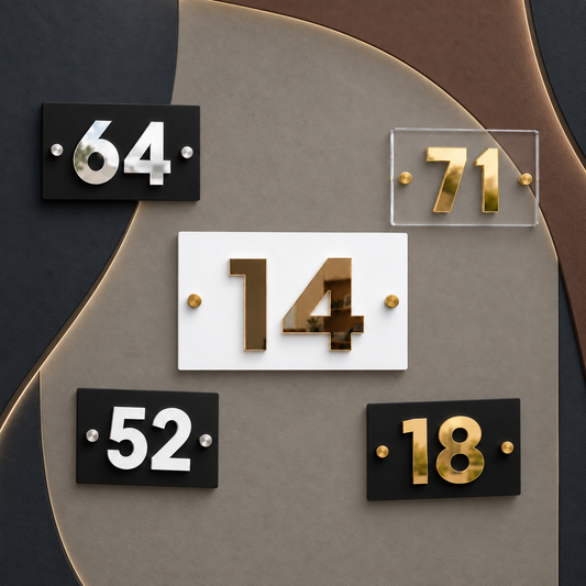 Modern house number plaques arranged on a decorative wall. The central plaque shows the number 14 in metallic gold on a white rectangular background.lumorastudio.ie lumora craft studiopersonalised-compact-acrylic-house-plaque